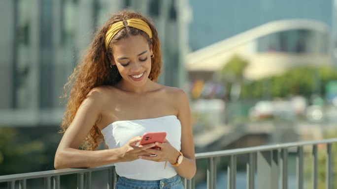 女人，开心的笑和电话在城市的桥上用手机短信和社交媒体应用程序。户外城市和年轻的女人用青春和网络聊天用