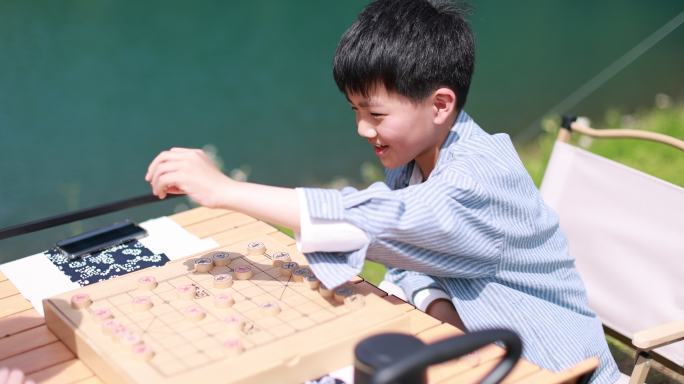 在湖边下棋的中国男孩