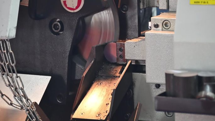 近距离拍摄带锯切割机切割金属轴类零件的操作场景。