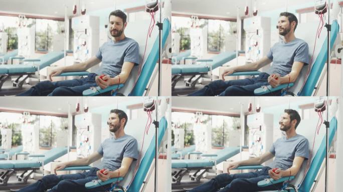 白人男子在光明医院为有需要的人献血。男性献血者挤压心形红球，将血液通过管道泵入袋中。捐赠给与癌症抗争