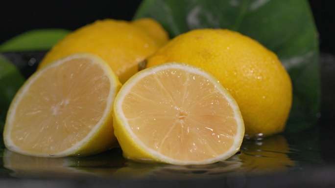 异国情调的水果，成熟多汁的柠檬用干净的淡水浇灌在黑暗的背景上，特写