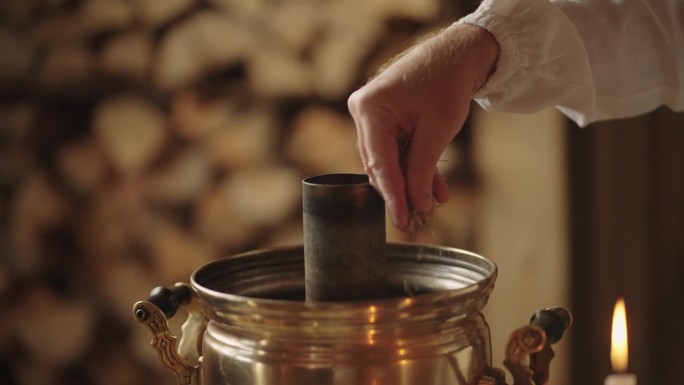 老俄罗斯风格的传统茶道，男子在茶炊中将草药倒入水中，特写