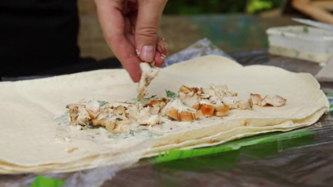 双手将馅料铺在皮塔饼里，在夏天的野餐、户外聚会上烹饪沙瓦玛