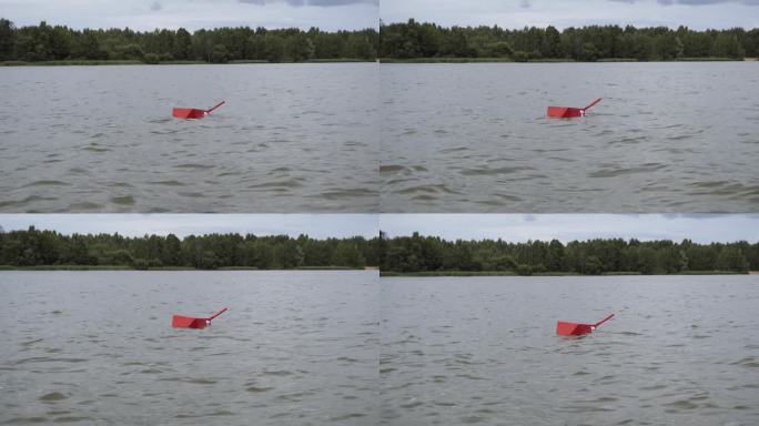 带手柄的红色浮标在森林岸边附近的河流中摇摆。