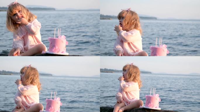 一个小女孩穿着粉红色的衣服，坐在那里吃着粉红色的蛋糕，拿着三支蜡烛和一支笔，背景是美丽的大海，晚上阳