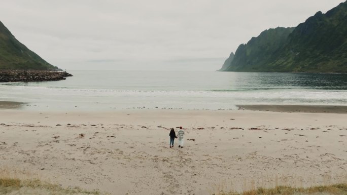 无人机跟随一对快乐无忧无虑的年轻夫妇奔向厄斯峡湾海滩