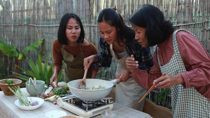快乐的亚洲家庭在房子的露台上一起准备传统的泰国米饭-母亲和女儿闻到新鲜的食物