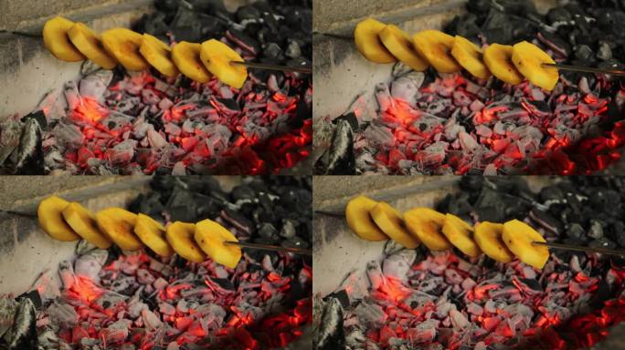 切成大块的土豆串在木炭烤架上烤熟。