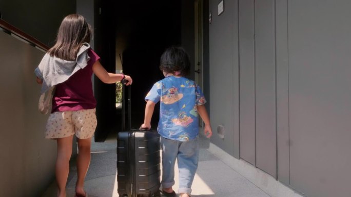 亚洲同胞在酒店度假时提着行李走在房间门口。