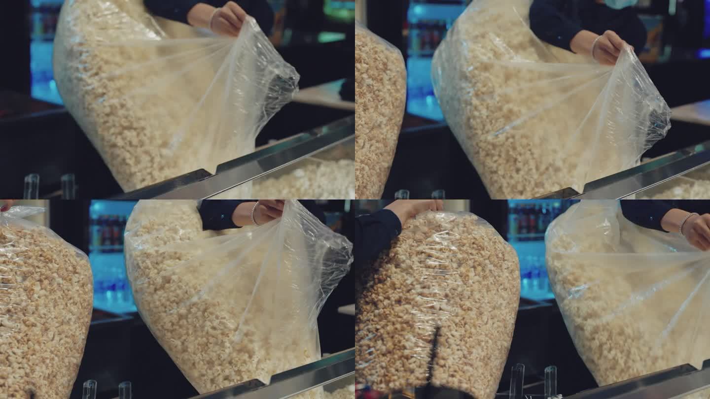 在电影院前，袋子里的爆米花正被倒入爆米花机。
