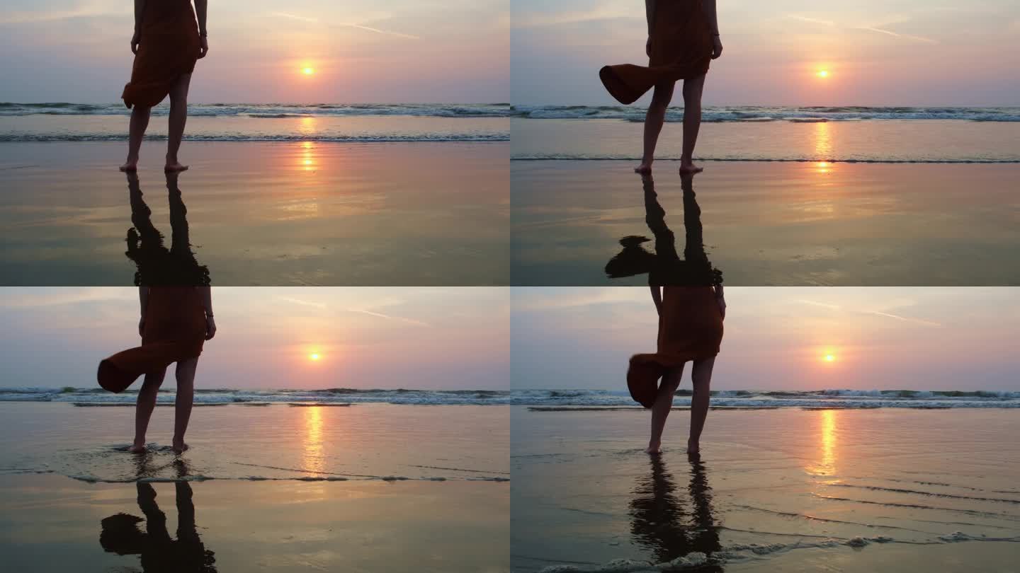 日落时分，女游客赤脚站在海边。黄昏中，女人站在海边，长裙随风飘动。自由和放松的概念。