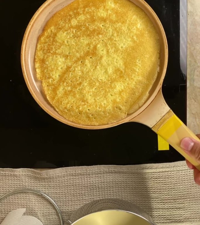 垂直视频视频厨师熟练地抛出薄的黄色煎饼，并抓住它在锅里