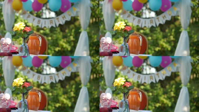 左边是阳光下的花朵，背景是生日派对的装饰品。在阳光明媚的夏日与人们在公园里吃着甜美可口的食物和饮料。