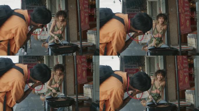 一名亚洲男子在老城区旅行时，用相机拍下了正在烤食物的女友。