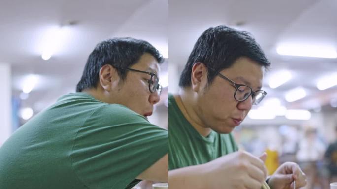 一名亚洲男子用筷子夹着米饭吃猪骨