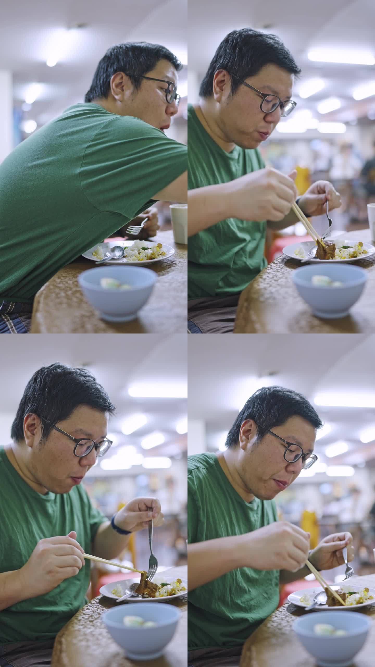 一名亚洲男子用筷子夹着米饭吃猪骨