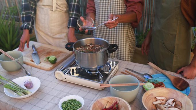 一个亚洲家庭在后院准备传统的泰式汤——母亲在汤里加酱油