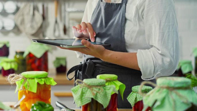 活跃的女人在一个电子平板电脑上输入关于家庭厨房机器人工作结果的数据