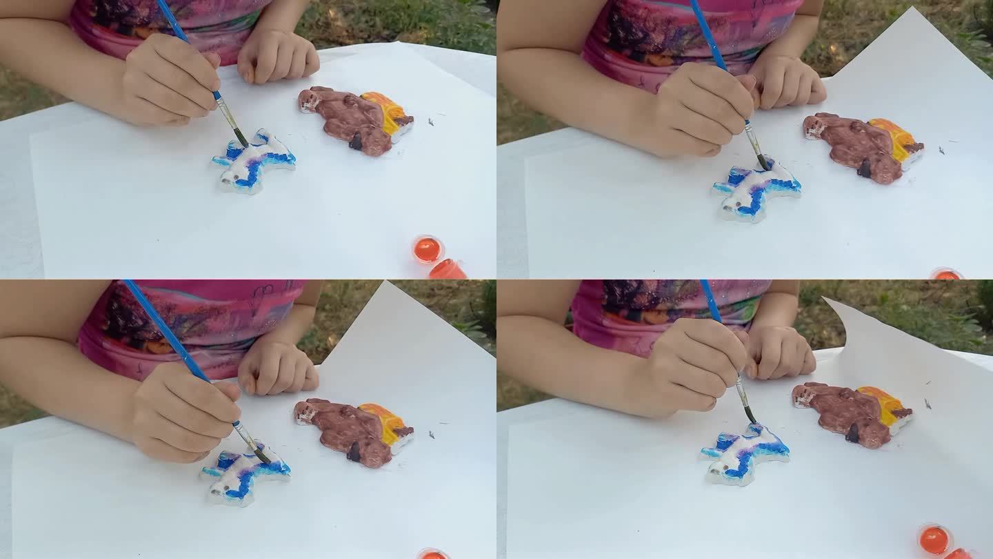 一名女小学生正在用颜料画石膏玩具。小孩的手特写。发展创新能力，精细运动技能。夏天。户外