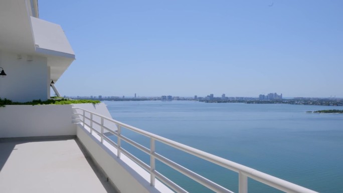 从阳光明媚的迈阿密海滩白色高档顶层公寓的阳台上欣赏威尼斯群岛迷人的风景。在夏天度假和放松的概念