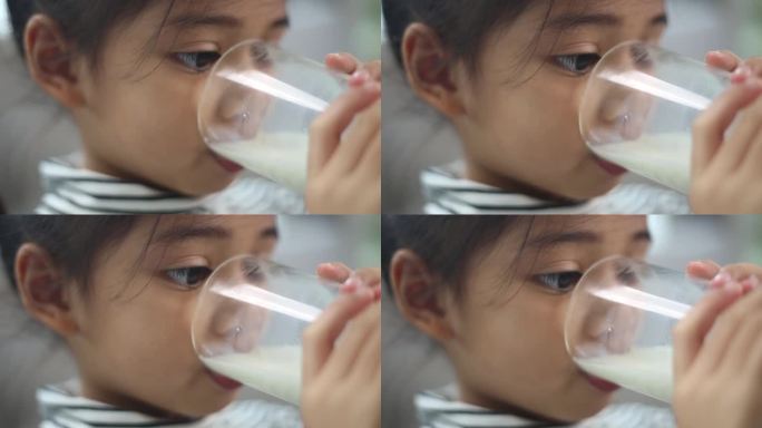 亚洲可爱的小男孩在家里拿着一杯牛奶。感觉快乐，享受喝牛奶。