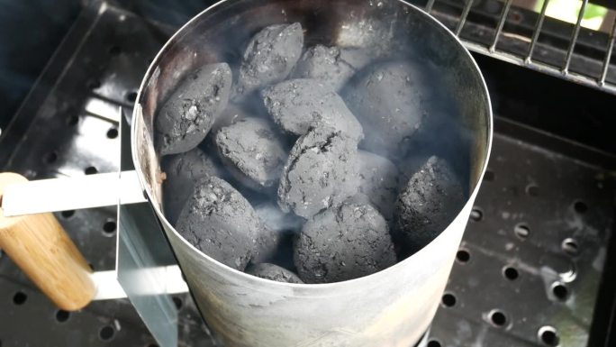 烟囱烤架起动器。冒烟的木炭烧烤煤块。