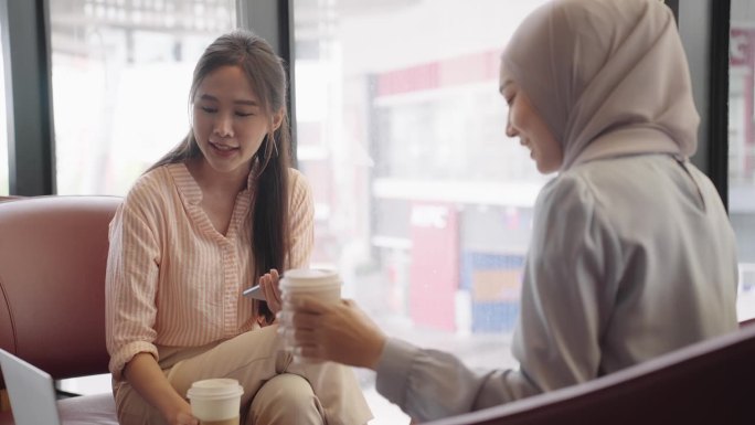 一名亚洲穆斯林妇女在咖啡店与朋友交谈