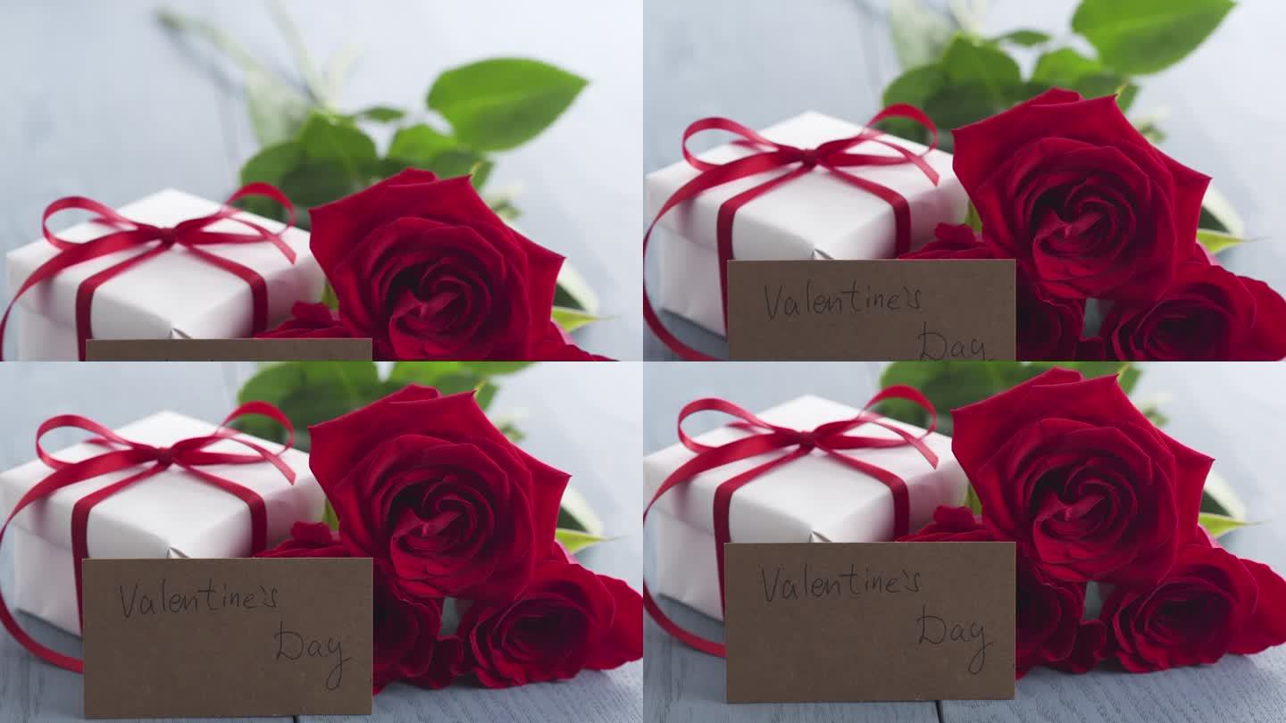 三红玫瑰与礼盒和纸卡与情人节的短语在蓝色的木桌盘