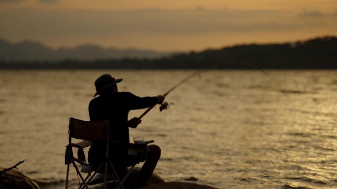 渔民的剪影独自休闲与鱼竿户外捕捉生活鱼在日落