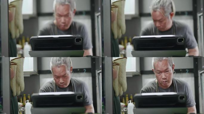 亚洲父亲一边在家洗奶瓶，一边用平板电脑看电影。