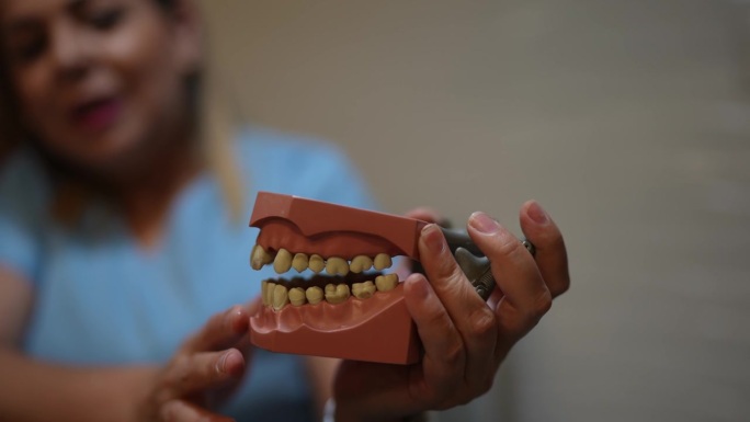 牙医在办公室向病人解释假牙的用法