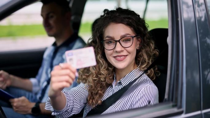 年轻的女学生在车里拿着她的新驾照