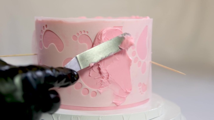 一个家庭洗礼蛋糕的装饰，粉色蛋糕上天使翅膀上有小孩的脚印，婴儿穿着粉红色的尿布，一个女孩如何在蛋糕的