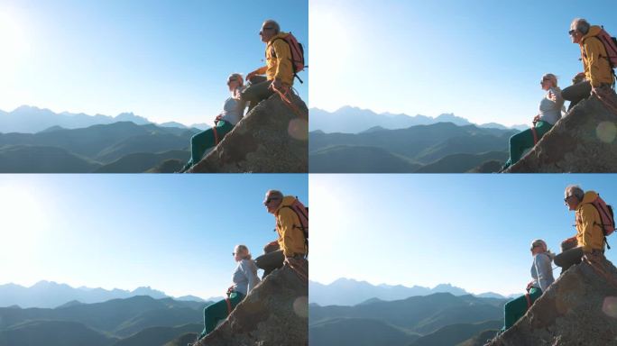 成熟的夫妇爬上山顶的岩石板
