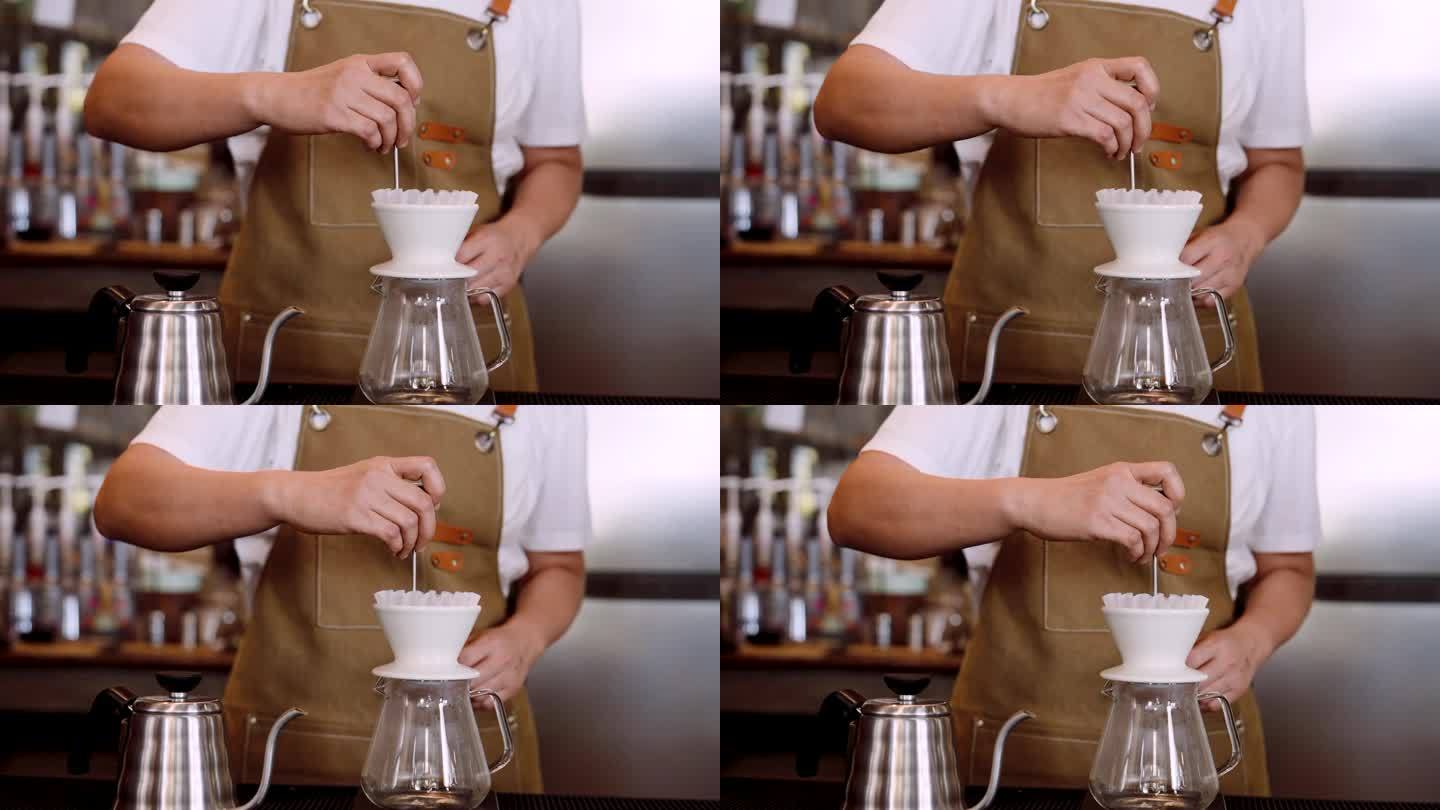 与咖啡师一起设置滴滤咖啡机，咖啡师在咖啡馆里用锋利的工具将一些滴滤咖啡抖掉，使其不会聚集在一起，以便