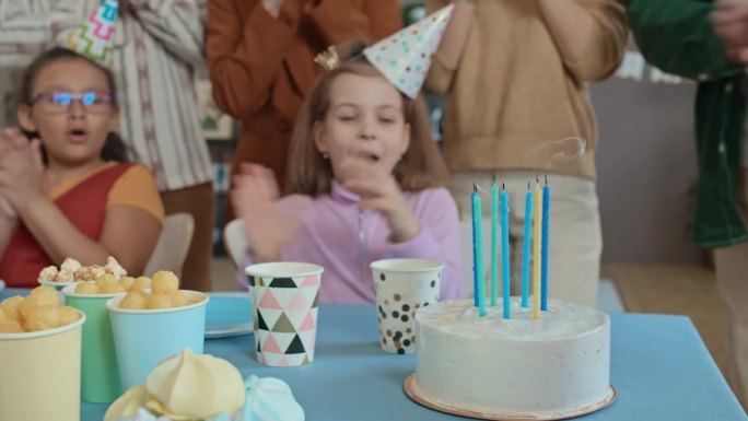 面目全非的孩子吹灭生日蛋糕上的蜡烛，客人鼓掌