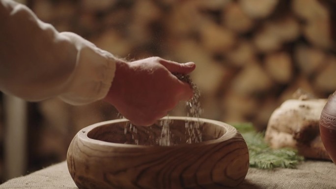 一名男子从餐桌上的木碗中取出谷物，在古老的斯拉夫村庄，古老的乌克兰风格
