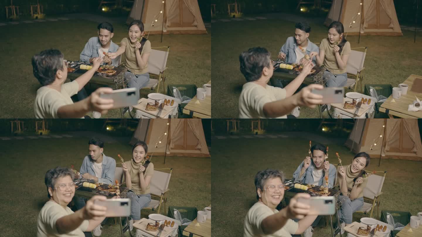 快乐的男人和女人在露台的餐桌上与家人自拍。兴奋地微笑着享受黄昏的烧烤野餐。