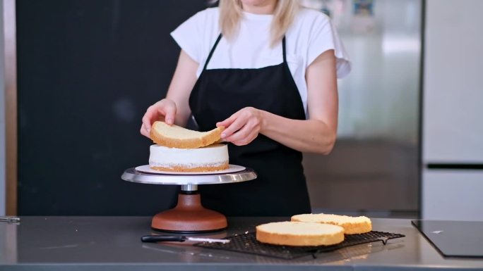 满意的金发女人微笑着连接着涂有甜奶油的新鲜蛋糕层