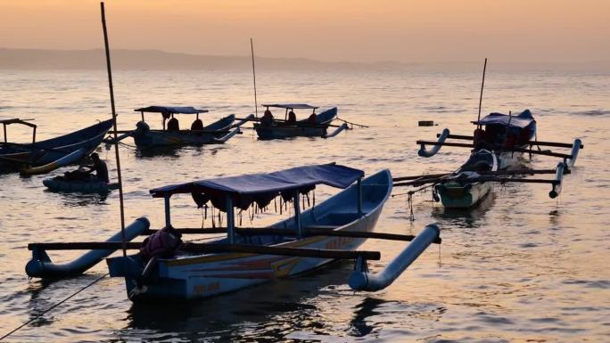 清晨，在日出前的Pangandaran海滩上，渔船停泊在波浪中摇晃，远处有雾和小船。中镜头和手持。