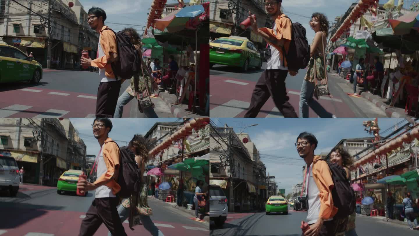 在曼谷唐人街，一对亚洲夫妇手拉手小心翼翼地走在人行横道上。