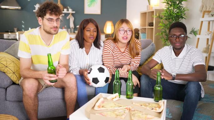 一群不同种族的年轻男女朋友在电视上观看足球比赛