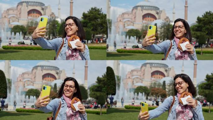 一名年轻女子在伊斯坦布尔圣索菲亚大教堂前边吃土耳其百吉饼边自拍