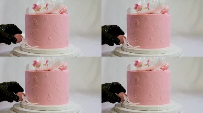 一个家庭洗礼蛋糕的装饰，粉色蛋糕上天使翅膀上有小孩的脚印，婴儿穿着粉红色的尿布，一个女孩如何在蛋糕的