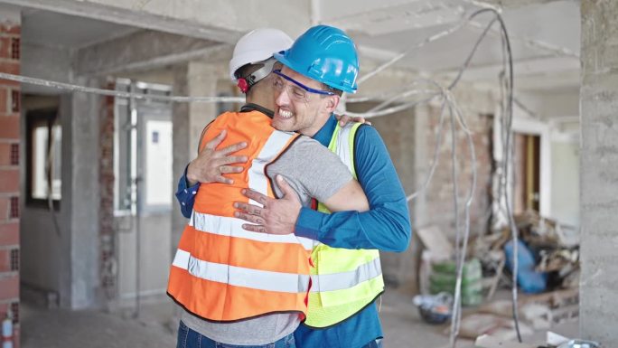 两名男建筑工人在建筑工地互相拥抱击掌