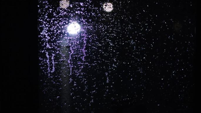 路灯照亮了防蚊纱窗上的雨滴。