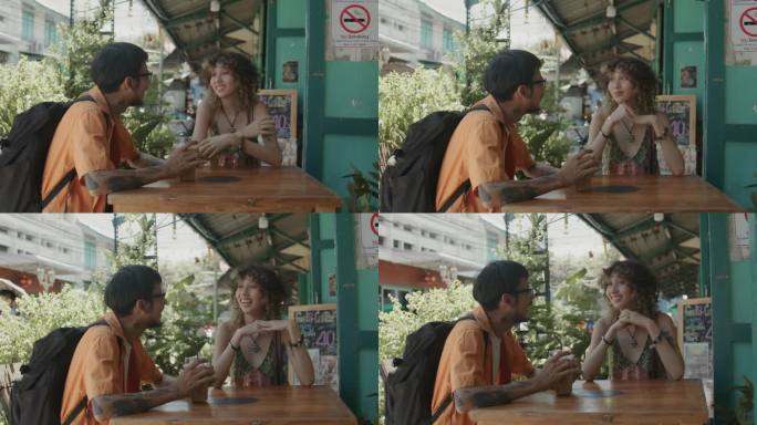 亚洲恋人坐在咖啡厅前聊天，享受美味的咖啡。