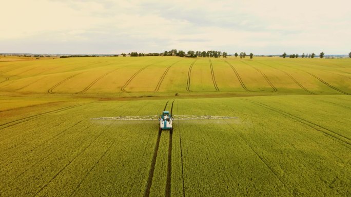 作物喷雾器在麦田喷洒农药鸟瞰图。拖拉机和作物喷雾器保护装置提高大麦产量