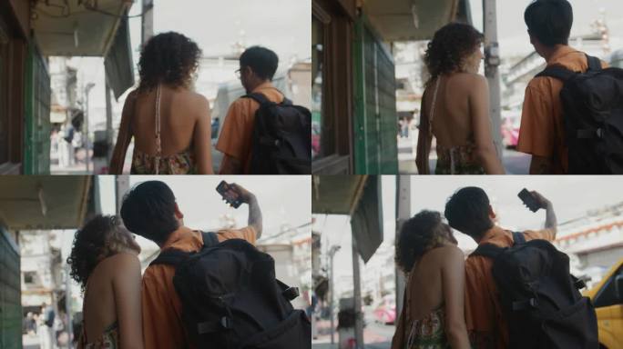 年轻夫妇走在街上，用智能手机在城市里自拍，度过了快乐的假期。