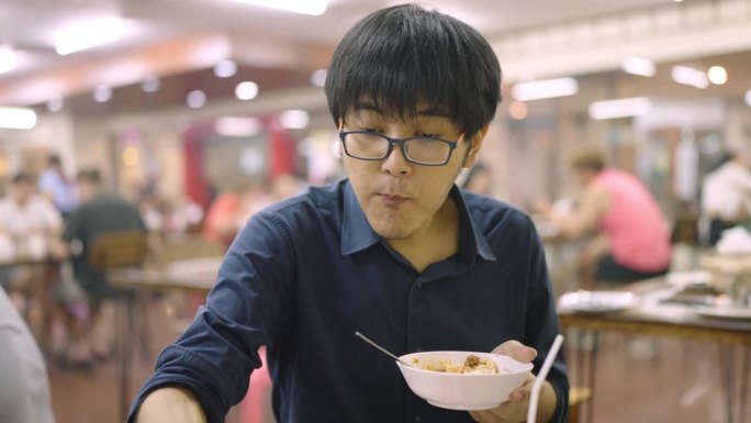 一个戴眼镜的亚洲人在中餐馆里吃喝